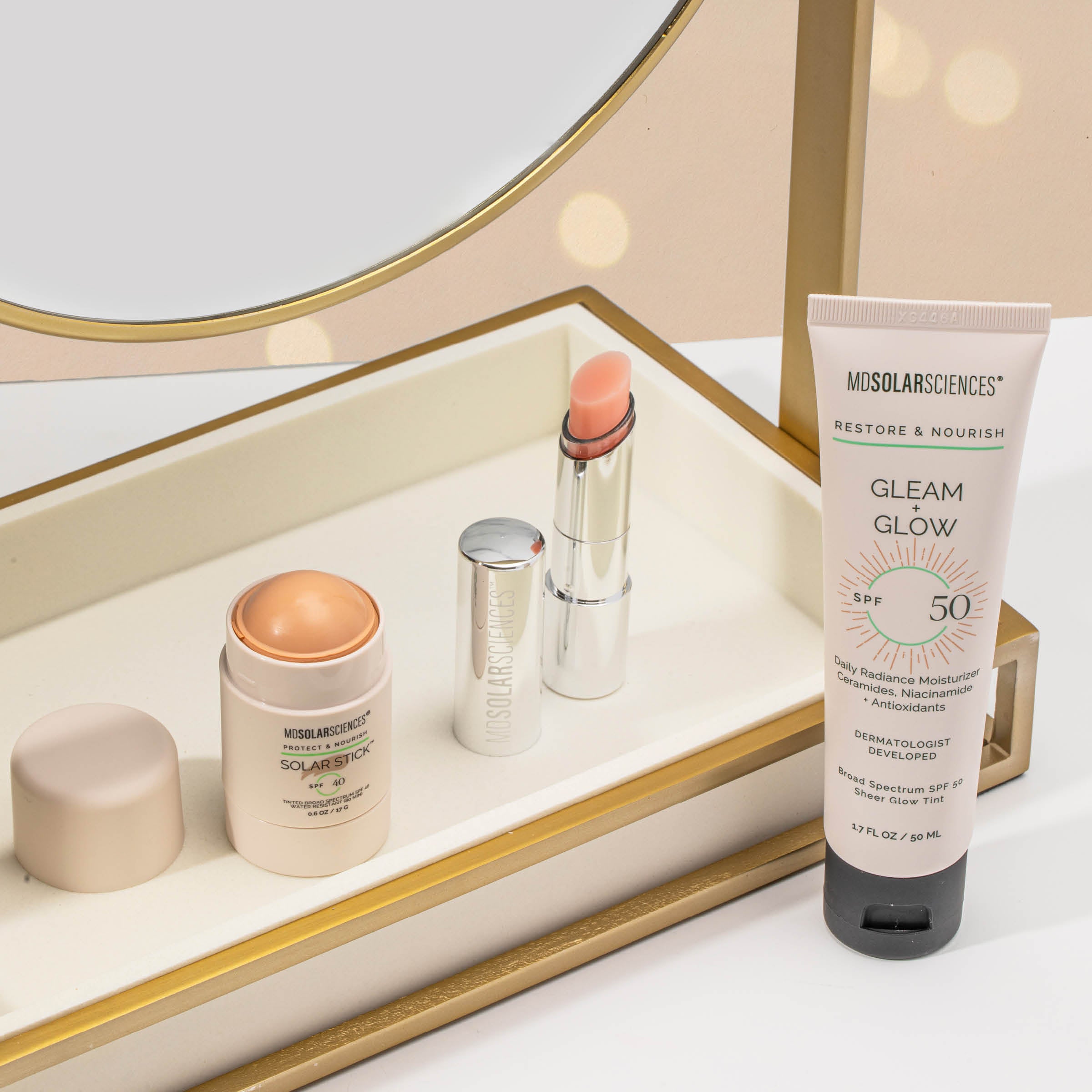 Cosmetic products including a tube of sunscreen, lipstick, and cream on a reflective surface.