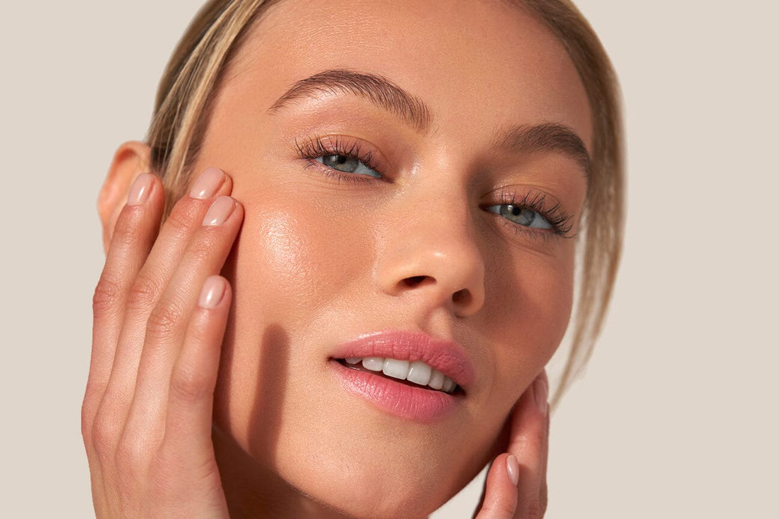 Dewy skinned woman is delicately touching her face